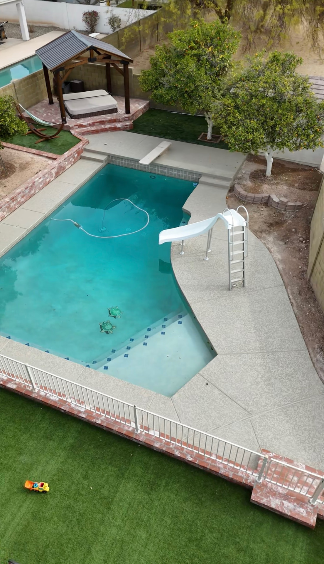 Gray textured acrylic pool deck resurfacing with slide and diving board