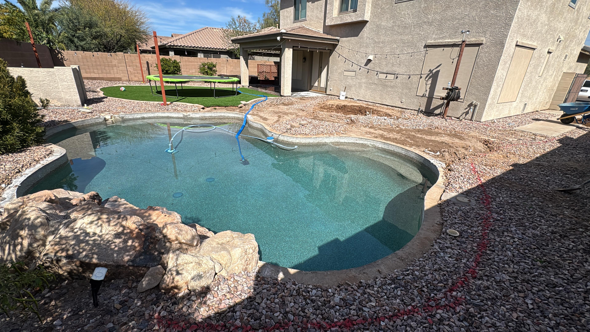 Backyard pool with dirt and no pool deck before resurfacing