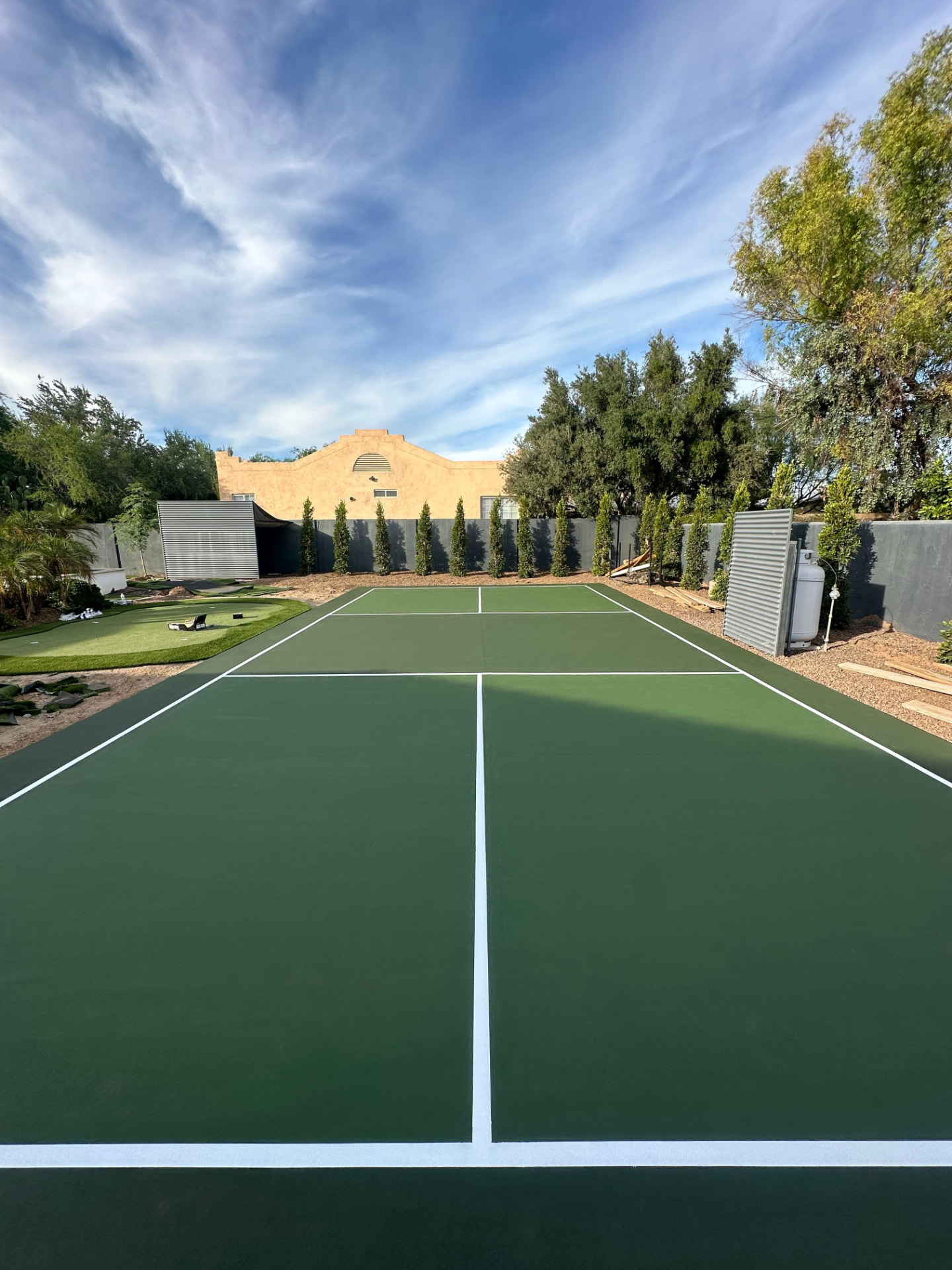 Deep green backyard pickleball court with white regulation striping