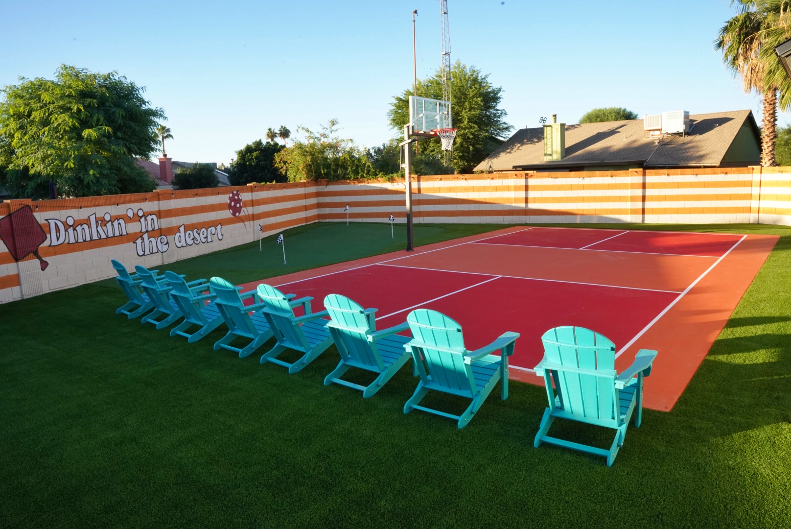 Red and coral pickleball court with turf surround and custom wall mural