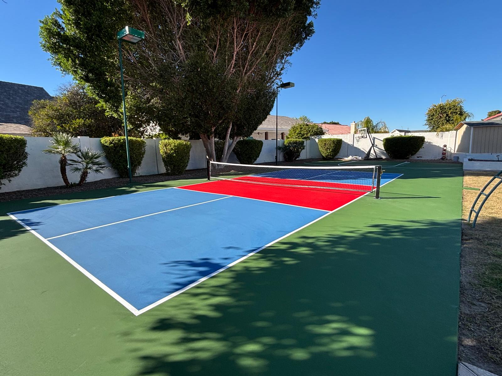 Green and blue backyard pickleball court with red kitchen zone